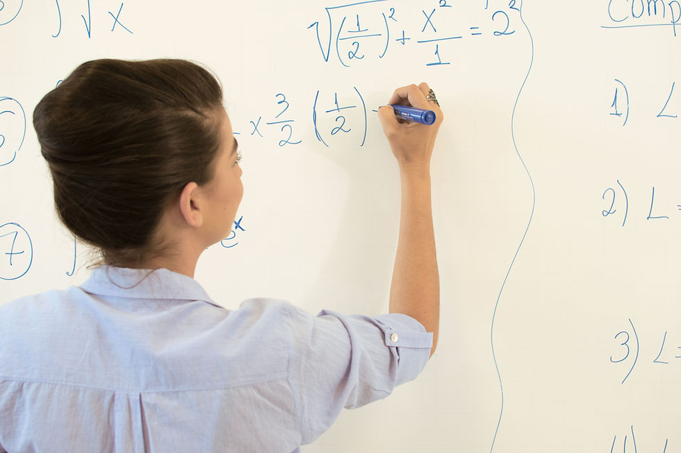 A tutor writing a maths formula on a whiteboard
