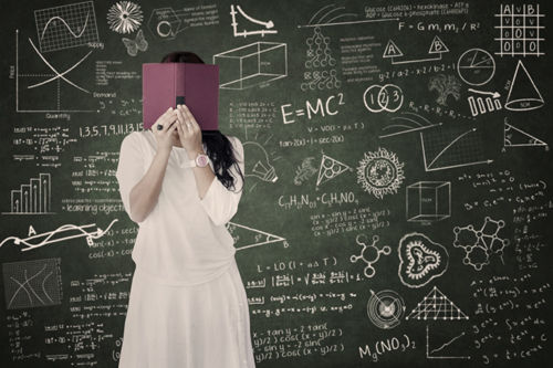 A tutor writing a maths formula on a whiteboard